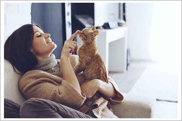 Happy insured homeowner relaxes in home with cat