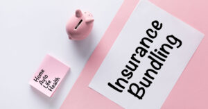 Insurance bundling written on paper with pink and white background and piggy bank on background